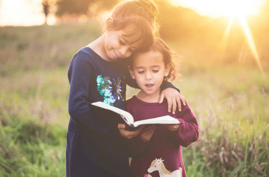 Niñas leyendo la Biblia al atardecer